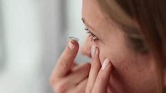 Woman puts contact lenses on eyes with finger, closeup. Contact lenses for eyes and instructions for use