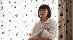 Eine taiwanesische Mutter in ihren Zwanzigern foltert ein 1 Monat altes Mädchen vor einem Vorhang im Haus.
