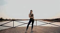 Young athletic woman doing fitness exercises in the park near the lake at sunset.Sporty life concept