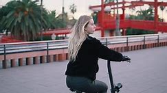 Pretty blonde woman driving electric scooter bike. Modern city transportation