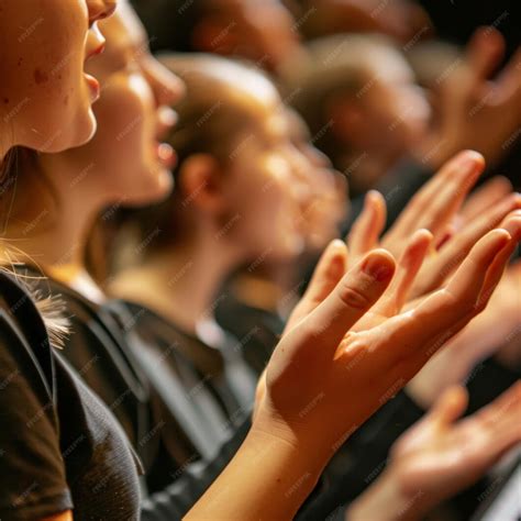 A closeup of hands and faces of several people singing together in a ...