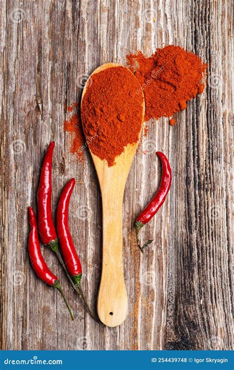 Ground Red Pepper in a Wood Spoon with Fresh Pepper Pods on a Textured ...