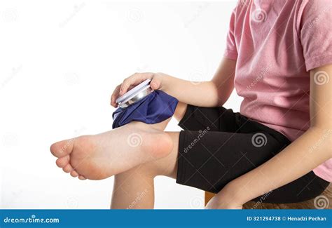 A Girl Applies a Blue Medical Bag with Ice To Her Ankle Joint for a Bruise on Her Leg. Local ...