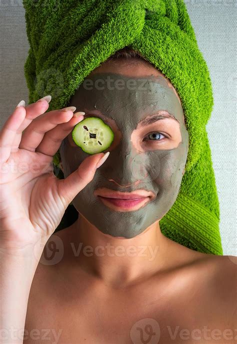 Beautiful young woman with facial mask on her face holding slices of ...