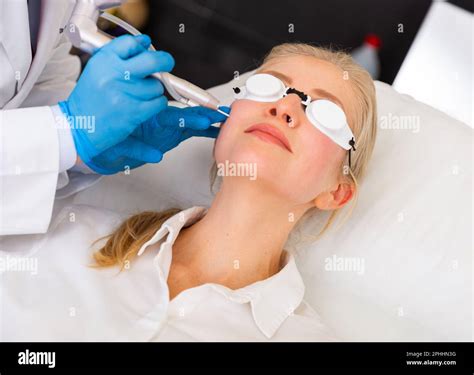 Cosmetologist doing laser wart removal procedure for young woman Stock Photo - Alamy