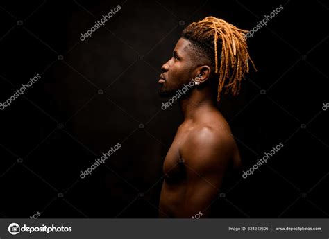 Side view naked black guy with blonde dreadlocks posing in the studio ...