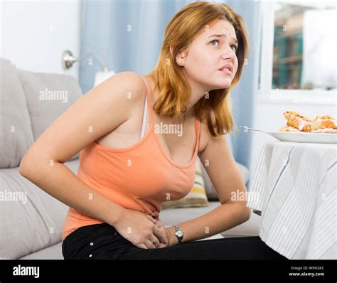 Girl is having a stomach ache after eating many cake at home Stock Photo - Alamy