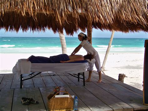 a woman getting a back massage on the beach under a thatched roof over ...