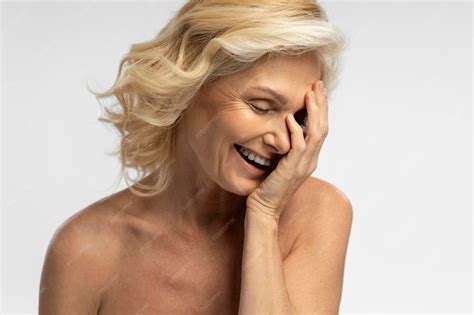 Delightful naked blonde mature woman laughing isolated over white background copy ad space ...