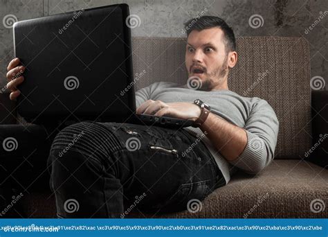 A Man Watches an Adult Video on a Laptop while Sitting on the Couch ...
