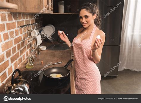 Sexy Young Woman Apron Holding Eggshell Smiling Camera While Frying Stock Photo by ©DmitryPoch ...