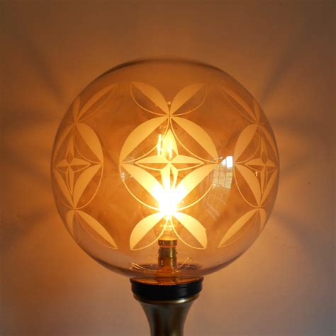 A bespoke gold and navy floor lamp with a vintage glass globe shade