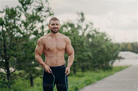 alegre deportista sin afeitar salta con cuerda, tiene cuerpo musculoso ...