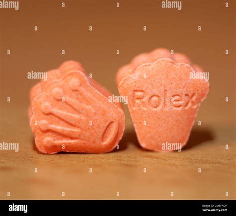 Orange pills with mdma ecstasy dope rolex drug close up background fine art in high quality ...