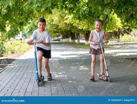 Two Children Ride on Scooters on Street Sidewalk in City Outdoor ...