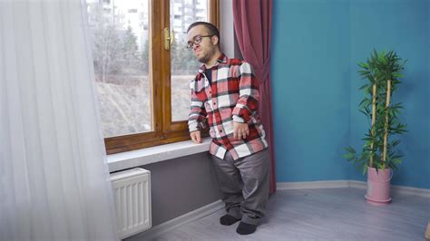 Crying dwarf man looking out the window at his house. The dwarf man is ...