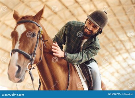 Sitting in the Saddle. Young Man with a Horse is in the Hangar Stock ...