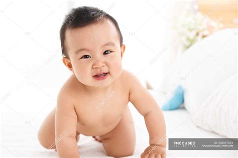 Cute happy asian baby boy crawling on bed and looking at camera — 6 12 ...