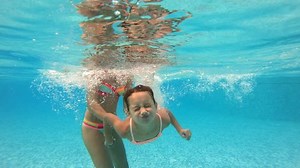 Little girl swimming underwater in the pool. Slow motion