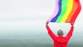 Hombre levantar bandera LGBTI de color arco iris ondeando en duro...