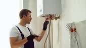Professional engineer installing a natural gas boiler at home, he is...