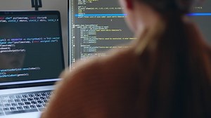 Young Asian woman, developer programmer, software engineer, IT support, wearing glasses working hard at night overtime on computer to check coding in bugging system.