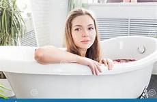 bathroom girl relaxes petals attractive takes against flower young light background beautiful spa interior bare clean