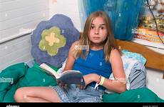 preteen girl bed sitting her book reading long haired blond alamy