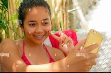 asian bed girl bikini selfie relaxed sarong indonesian teenager sitting taking alamy pool mobile phone happy young beautiful