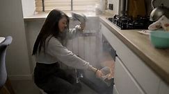 Long haired woman opening smoke filled oven in the kitchen