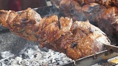 Fatty, unhealthy, partially burnt meat with cholesterol and carcinogens. Meat are cooked on hot coals in chargrill or charcoal brazier. Big fat shish kebab broils in barbecue