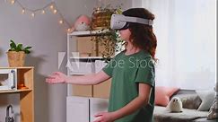 redhead teen girl at home in living room put on vr helmet to enjoy virtual reality online game cyber space world simulation. cute girl has fun using new electronic device for entertainment