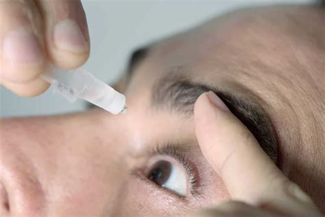 man applying eye drops to his eyes - Cyber Athletiks