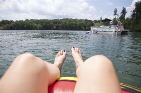 $160.00 per day plus tax. Woman relaxing in tube on lake while looking at pontoon ...