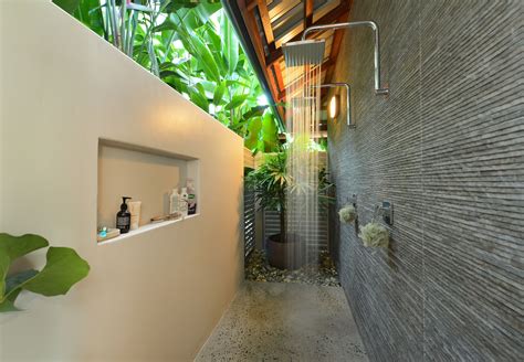 An outdoor shower featuring lush greenery complemented by a concrete wall and slatted wood flooring make for the perfect tropical escape. Indoor/Outdoor tropical designed shower. | Outdoor remodel ...