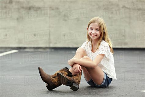Smiling girl wearing cowboy boots in parking lot - Stock Photo - Dissolve