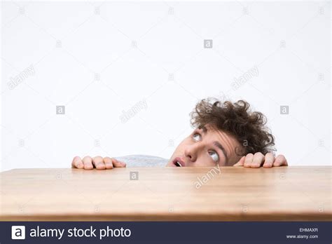 Handsome man peeking from behind the desk Stock Photo - Alamy