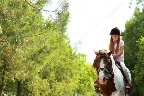 Perfectly timed photos are what photography is all about! Cute little girl riding pony in green park - Stock Photo ...