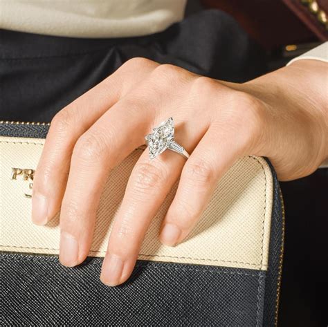 The shoulders are each channel set with three (3) baguette cut diamonds bezel set on the side and bordered with milgrain edging. 4.18-Carat Marquise-Cut Diamond Ring