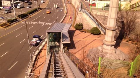 Dia memutuskan untuk mengambil jalan pintas. Lif funicular dari kaki bukit Namsan ke Stesen Bawah ...