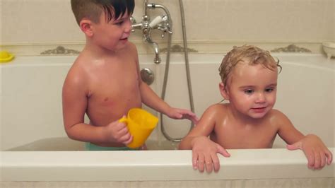 Keep your little one cozy. Litttle boy washing his younger brother in a bath Stock ...