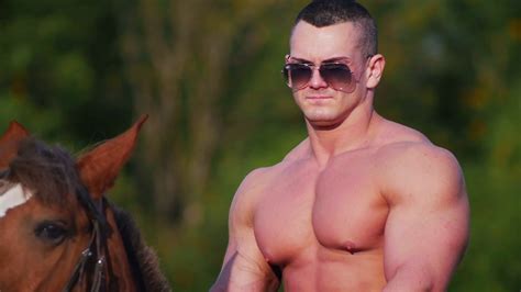 A strong man with a powerful chest in sunglasses riding a horse in ...