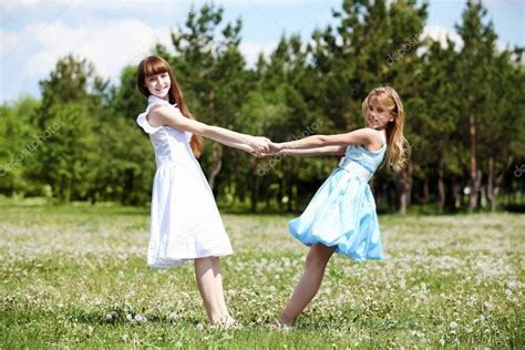 Childhood, education, holidays or homework concept. Two girls playing in the park — Stock Photo © SergeyNivens ...