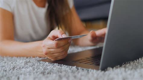 Lying on credit card application. Woman is lying on the floor and makes an online purchase using a credit card and laptop. Online ...