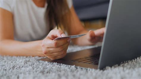 Lying on credit card application. Woman is lying on the floor and makes an online purchase using a credit card and laptop. Online ...