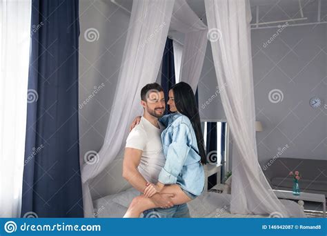 Love Is In The Air. Beautiful Young Couple Bonding And Smiling While Sitting In The Bedroom ...