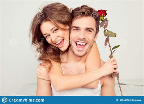 Cheerful Young Couple In Love Embracing In The Bedroom With Rose Stock Photo - Image of couple ...
