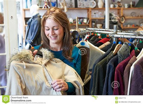 Female Shopper In Thrift Store Looking At Clothes Stock Photo - Image ...