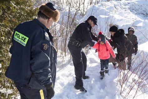 Border patrol guards and rosie the dog look on. With open arms, Mounties help refugees who walked across ...