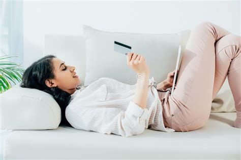 Maybe you would like to learn more about one of these? Latin Woman Holding Credit Card And Using Digital Tablet While Lying On Sofa At Home Stock Image ...